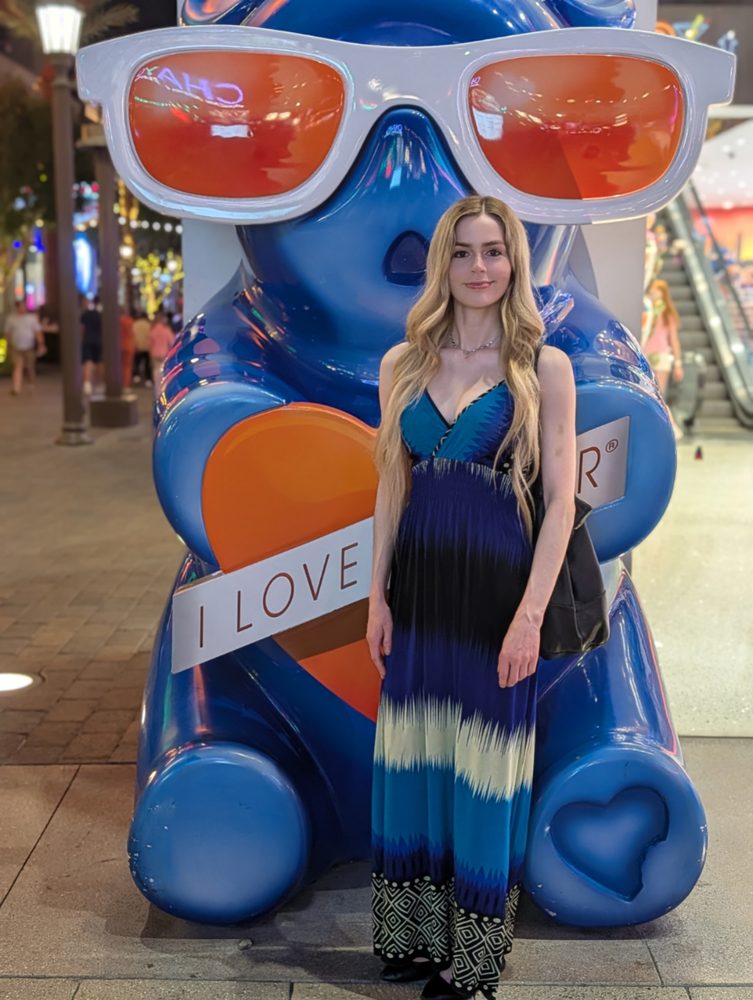 Pip in a long blue striped dress in front of a giant blue gummy bear statue